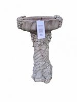 Front view of the concrete bird bath showing detailed grapevine decoration around basin rim and pedestal column