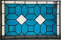 Full front view of stained glass panel showing blue and white geometric pattern and black leading.