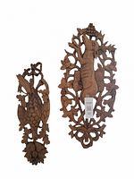 Photo showing two vertical wooden carvings mounted on a white wall: larger squirrel carving and smaller bird carving with pinecone motifs