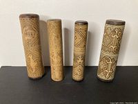 Four vintage bamboo betel nut containers standing vertically showing carved traditional patterns and animal motifs.