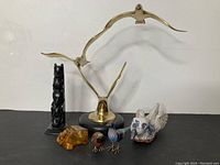 View of all six figurines showing brass birds on marble base, carved black totem pole, amber bear, cloisonne birds, and ceramic bird.