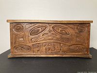 Front view of the wooden box showing detailed carvings of traditional West Coast Indigenous art.