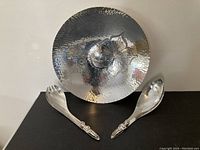 Overall view of hammered bowl with floral design and pair of serving utensils with humanoid figure handles