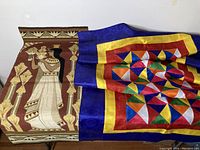 Both textile wall hangings laid side by side showing their main designs and colors.