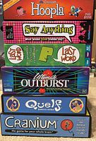 Photo showing six boxed family board games stacked vertically: Cranium Hoopla, Say Anything, Last Word, Ultimate Outburst, Quelf, and Cranium.