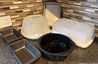 Photo showing two bread loaf pans, a black silicone Bundt pan, and two Wilton cake/cupcake carriers with clear lids.
