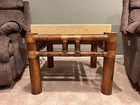 Front view showing the wooden bamboo-style base and thick faux stone top of the side table