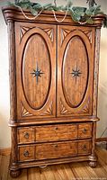 Full front view of the brown wooden Broyhill Tropical Retreat armoire with carved details and woven bamboo panels on the doors and drawers.