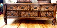 Front view of the wooden tropical coffee table showing the three drawers and carved wood details on the front and legs