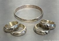 Silver bangle and four silver rings showing designs and details from above