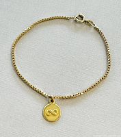 Full view of yellow gold box chain bracelet with attached infinity charm