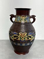 Front view of antique Asian bronze cloisonné vase showing colorful enamel patterns and two animal head handles.