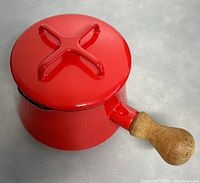 Red enamel Dansk Kobenstyle saucepan viewed from above with lid on, showing X-shaped lid handle and natural wood handle