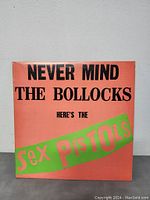 Front cover of the vinyl album showing title and band name with bright orange background and black/green/pink lettering.