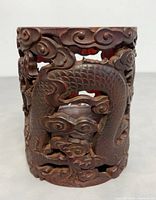Front view of the carved dragon detail on bamboo brush holder showing intricate openwork design and texture.