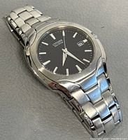 Close-up angled view showing stainless steel bracelet, round case, black dial with date and Eco-Drive text.