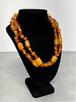 Photo of amber necklace on a black display stand showing double strand and bead shapes and colors.