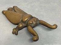 Top view front of solid brass scarab beetle door stopper showing detailed beetle shape and patina.