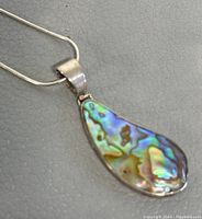 Close-up of the drop-shaped abalone pendant with silver setting showing iridescent shell pattern.
