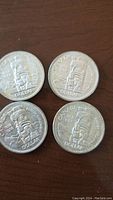 Four silver dollar coins showing reverse totem pole design