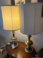 Two matching brass lamps on wood table, one illuminated