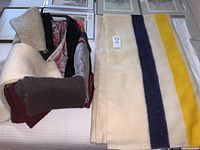 Overview of folded Hudson’s Bay blanket with colored stripes and box containing scarves and gloves