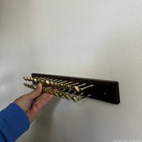 Side view of tie rack showing brass golf club hooks extending from wooden plaque