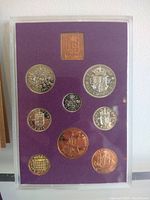 Photo of the coin proof set showing nine different British coins displayed on purple velvet backing inside a plastic protective casing.