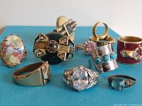 Overview of all nine vintage rings showing various designs and colors on a blue background.