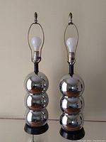 Full front view of two vintage stacked chrome ball lamps on black bases