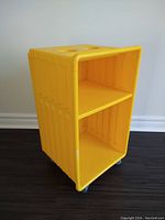 Yellow plastic IKEA Didrik rolling storage cart side view showing shelves and ribbed design