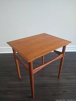 Full view of teak side table showing square top and slender legs.