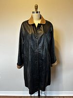 Front view of black leather long coat with tan suede collar and cuffs on dress form.