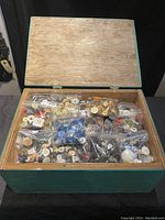 Open vintage wooden box containing 54 clear plastic bags filled with assorted buttons of various colors and materials.