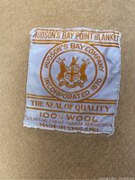 Close-up of the Hudson's Bay Company label on the wool blanket showing branding and material information.