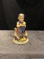 Front view of the girl holding a chick with two chickens and two chicks at her feet on a textured surface.