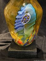 Close-up of the vase detailing showing multicolored glass design with yellow, blue, green accents on the outer surface