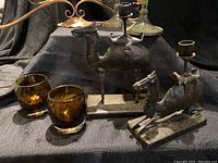 Photo showing two metal camel candle holders, two amber glass votive holders, metal candelabra, tall metal candlesticks