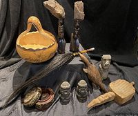 Overview of lot showing carved wooden figurines, pottery basket, broom with carved handle, decorative boxes, and stone bust heads
