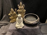 Lot showing three statues (seated Buddha and two gold-toned deity figures) and one decorative black bowl with floral pattern