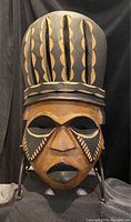 Front view of the carved wooden tribal mask showing face details and headdress pattern.