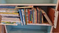 Shelf view showing various children's books stacked horizontally and vertically showcasing spines with titles and authors visible.
