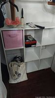 Overall view of white cubicle organizer in closet with pink fabric drawer in top left compartment, some personal items around it not included in sale