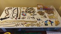 Full view of assorted jewelry on a table showing necklaces, earrings, pendants, bracelets, and beads.