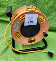Front view of orange Quad Top Cord Reel Model 2000 with yellow extension cord and four outlets visible on the reel center.
