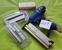 Campbell Hausfeld 2-in-1 air nailer/stapler with three packs of metallic staples of different sizes on a green surface.