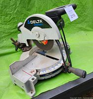 Right front angled view of Delta ShopMaster Chop Master cut off saw showing 7 inch metal disc and handle, placed on a green surface.