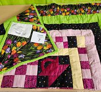 Close-up of corner with folded back showing tulip floral fabric and multi-colored patchwork front with geometric and floral patterns.