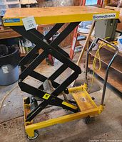 Front and side view of steel yellow and black high lift scissor cart on casters