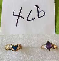 Two gold rings side by side on white foam against green background with handwritten number 46b above.